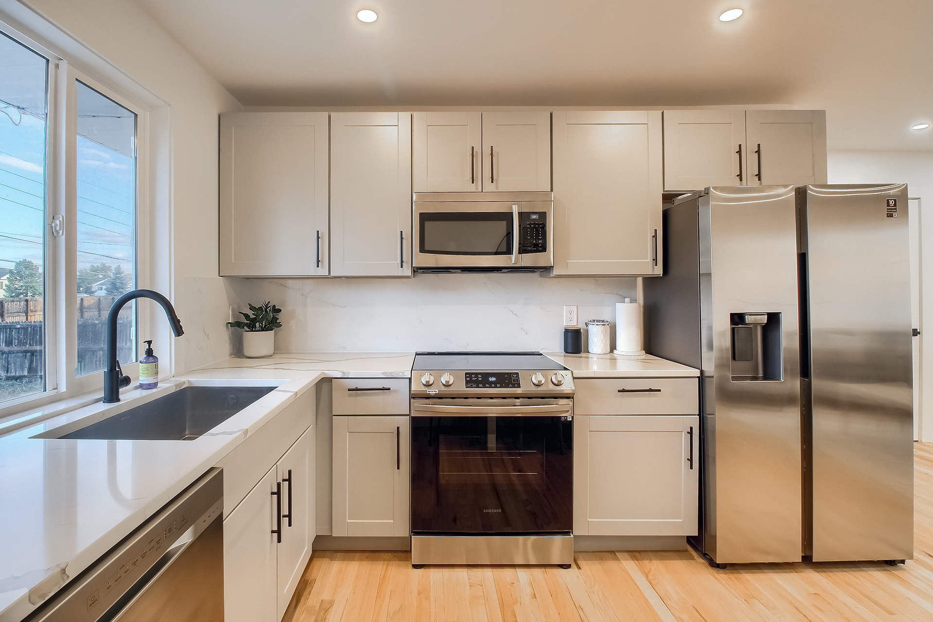 Kitchen remodel in Arvada with gray shaker cabinets, white quartz countertops and large format slab backsplash