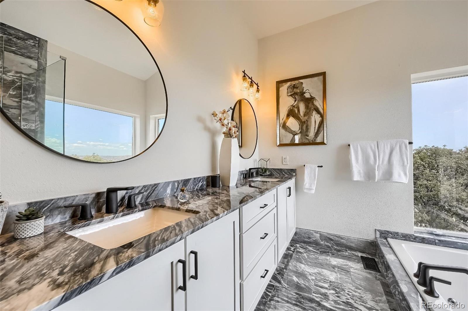 Luxury bathroom remodel in Castle Rock with natural stone tile, soaking tub and matte black fixtures