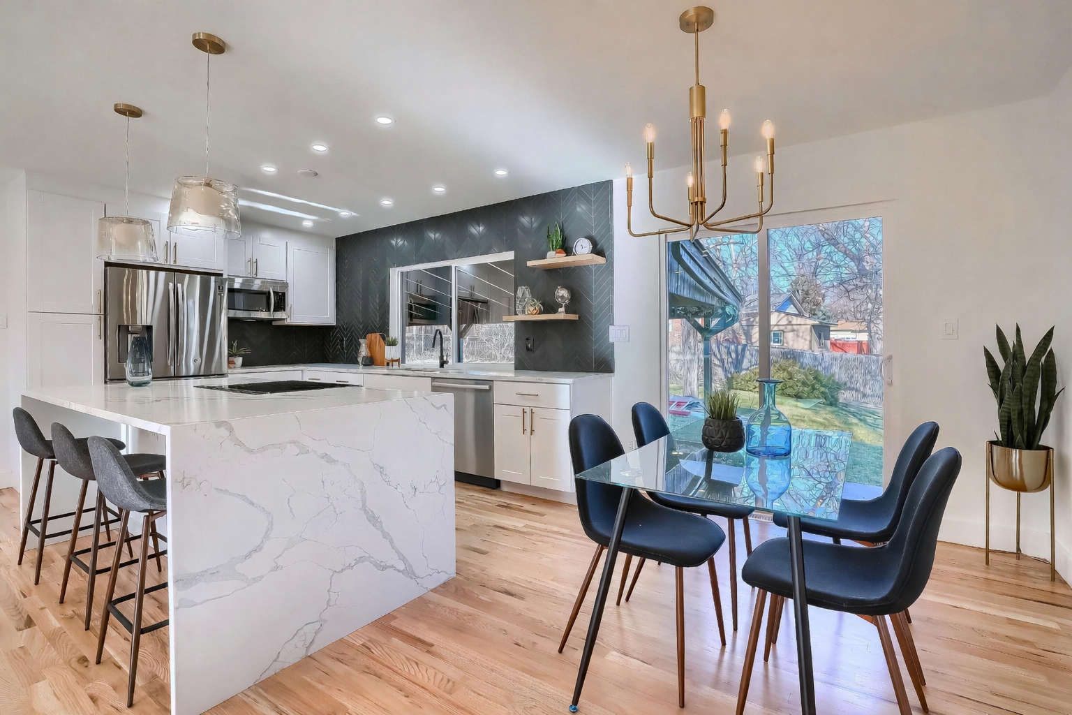 Full kitchen renovation in Denver with white shaker cabinets, Calacatta quartz waterfall island and custom black herringbone tile backsplash