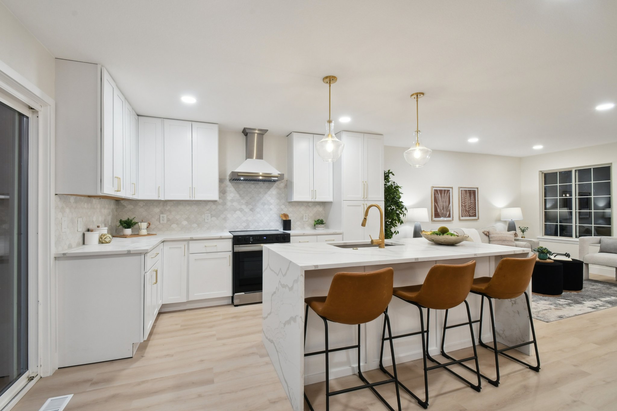 Kitchen remodel in Highlands Ranch featuring semi custom white shaker cabinets, marble backsplash, Calacatta quartz waterfall island and vent hood