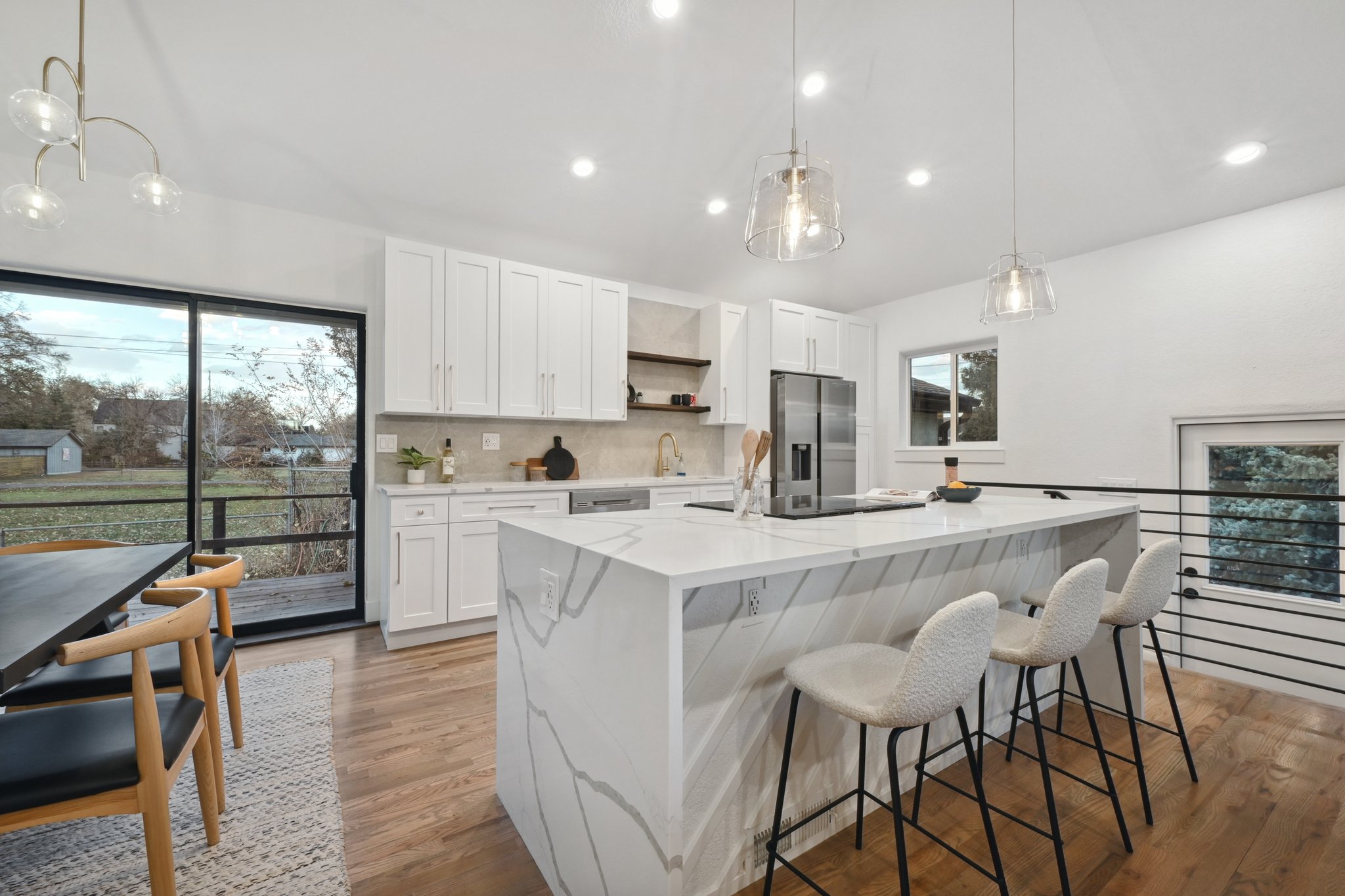 Full kitchen remodel in Lakewood featuring white shaker cabinets and Calacatta quartz waterfall island with vaulted ceilings